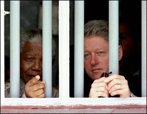 In this March 27, 1998 photo, South African President Nelson Mandela, left, and U.S. President Bill Clinton peer through the bars of prison cell No. 5, the cramped, gray cell where Mandela was jailed for 18 years in his struggle against apartheid, on Robben Island, South Africa.