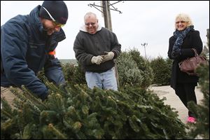 Dylan Willits, left, a sales associate at The Andersons, jokes with Roger and Sherri Kerner of West Toledo before taking their newly chosen tree to be wrapped up and trimmed on the Christmas tree lot at the company’s store in West Toledo. The store began the season with 1,190 fraser fir trees for sale.