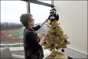 Jacki Way, admires the Christmas tree that she and a colleague decorated and topped with a Rocky Golf Head Cover for a driver for sale at UT  in the foyer of the athletics office.