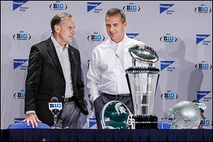 Michigan State coach Mark Dantonio, left, talks with OSU coach Urban Meyer during a news conference Friday in Indianapolis. Their teams will meet today for the Big Ten championship.