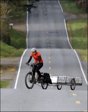 Heidi Lappetito zigzags her cargo bike across the road to help moderate the steep hill while hauling a trailer loaded with frozen salmon near Port Townsend, Wash.