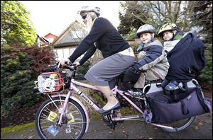 Madi Carlson, 41, pedals as her sons Rijder, 4, left, and Brandt, 6, ride aboard the family cargo bike throughout the Seattle area.