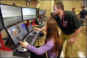 Start Freshman Mya Sanchez, left, listens as Rich Naves, training director, right, gives her a lesson on the simulator during a visit by TPS ninth graders to the Aviation Center to see if they are interested in enrolling in the district's 3-year Aviation Technician Program.
