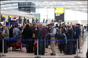Passengers queue at the flight check-in desk to re-book tickets at London's Heathrow Airport Terminal 5 after a 