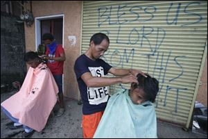 Typhoon survivors get a haircut along the streets for $1 in Tacloban, central Philippines on Sunday.
