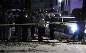 Bystanders, many of them reportedly family members of the slain men, watch as police investigate 2 deaths at a home on E. Pearl St. in Toledo, Ohio.