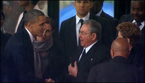 President Obama shakes hands with Cuban President Raul Castro at the FNB Stadium in Soweto, South Africa, in the rain for a memorial service for former South African President Nelson Mandela.