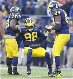 University of Michigan players Fitzgerald Toussaint (28) and A.J. Williams (84) helps quarterback Devin Gardner (98) to his feet. Gardner apparently incurred turf toe during this game Saturday, November 30, against Ohio State.