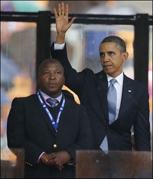 President Obama waves standing next to the sign language interpreter after making his speech at the memorial service for former South African president Nelson Mandela at the FNB Stadium in Soweto near Johannesburg.  South Africa's deaf federation said today that the interpreter on stage for Mandela memorial was a 'fake.'
