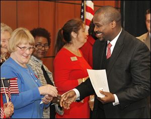 Chris Burkhart of the Fort Industry chapter of the Daughters of the American Revolution congratulates Andrew Mwangi Gitongu, who was among 39 people who became  citizens Thursday.