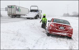 A wrecker driver removes a car that slid off the Ohio Turnpike westbound near the Maumee exit.