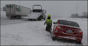 An ABCO worker removes a car that slid off the Ohio Turnpike westbound near the Maumee exit in Maumee.