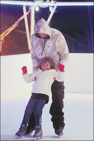 Mike Mayhugh, of South Toledo, holds up his daughter Mackenzie, 7, as the pair skate.
