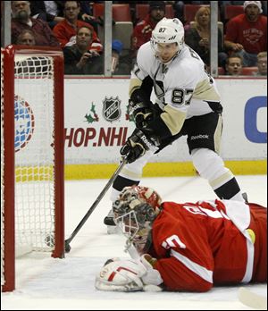 Pittsburgh Penguins' Sidney Crosby (87) works the puck around the goalpost to score against Detroit Red Wings goalie Jonas Gustavsson (50), of Sweden, during the first period.