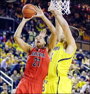 Arizona forward Brandon Ashley (21) makes a layup while being defended by Michigan forward Mitch McGary during the second half. Ashley had 18 points for the Wildcats as they held off Michigan.