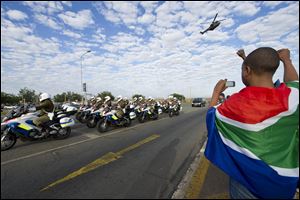 A child draped in the South African national flag gestures while taking a photo of the procession as the body of former president, Nelson Mandela arrives at the Waterkloof Air force base in Pretoria. From there it will be transported to Qunu for a state funeral on Sunday.