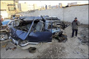 An Iraqi man inspects damaged vehicles in a car bomb attack in Baghdad, Iraq, today.