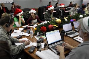 Lizzie Solano, center, and her sister Sarah take phone calls from children asking where Santa is and when he will deliver presents to their house, during the annual NORAD Tracks Santa Operation, at the North American Aerospace Defense Command, or NORAD, at Peterson Air Force Base, in Colorado Springs, Colo. last Christmas Eve.