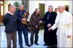 Pope Francis, right, is flanked by Vatican Almoner Archbishop Konrad Krajewski as he welcomes four men at the Vatican, today.