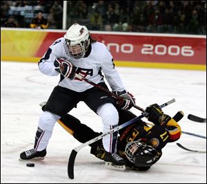 United States' Caitlin Cahow (8) upends Germany's Sara Seiler during the first period of a 2006 Winter Olympics ice hockey match in Turin, Italy. Cahow will join Deputy Secretary of State Bill Burns at the closing ceremony delegation of the Winter Olympics next year in Sochi, Russia. 
