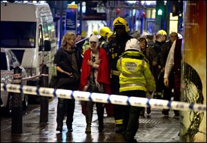 A woman stands bandaged and wearing a blanket  given by emergency services  following an incident at the Apollo Theatre, in London's Shaftesbury Avenue, Thursday evening.