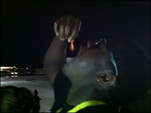 David Fatinikun holds his goldfish just above his mouth before dropping it in. 