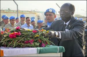 In this photo released by the United Nations Mission in South Sudan (UNMISS), South Sudan's Minister of Foreign Affairs and International Cooperation Dr. Barnaba Marial Benjamin lays flowers on the coffins of the two Indian peacekeepers who were killed on Thursday, at a memorial service held in the UNMISS compound in Juba, South Sudan, Saturday, Dec. 21, 2013.