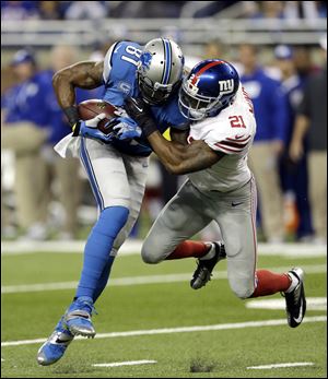Detroit Lions wide receiver Calvin Johnson, left, is stopped by New York Giants free safety Ryan Mundy during the first quarter Sunday in Detroit.