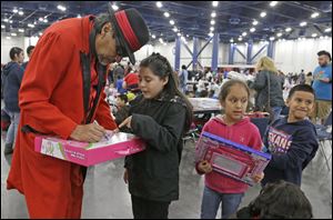 Pancho Claus, portrayed by Richard Reyes, autographs gifts at a charity holiday event Dec. 14, in Houston. 