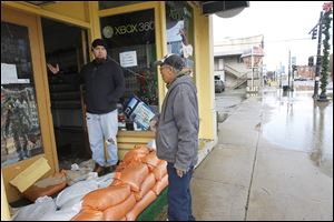 Stephen Scherger, left, owner of Flag City Gaming in Findlay, shows Boun Kantabouth the damage sustained by his store. The sandbags proved futile, but Mr. Scherger said Monday that he was able to save his merchandise.