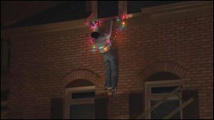 This frame grab from video provided by WSB-TV Atlanta shows an Atlanta homeowner's  Christmas decoration of a mannequin with outstretched arms entangled in a string of Christmas lights and clinging to a ledge.
