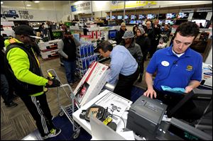 Best Buy employee Christopher Gervais, right, rings up a 32-inch LED TV in Dunwoody, Ga. on Black Friday.