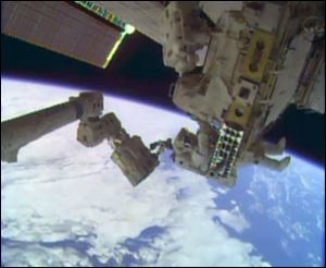 In this image taken from video provided by NASA, astronauts Rick Mastracchio, top, and Michael Hopkins work to repair an external cooling line on the International Space Station today, 260 miles above Earth.