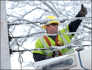 Dave Dora, an employee of a  Grand Haven utility company, gives a thumbs up to a worker as they reconnect fallen wires in Lansing. One utility firm said the wintry blast was the largest Christmas week storm in the company’s 126-year history. 