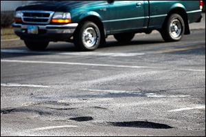 A truck passes through the intersection of North Wheeling and Consul streets in East Toledo. The recent fluctuation in temper-atures has caused potholes in many area streets and roads.