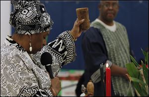 Rolita Noble uses a cup of water for the libation ceremony to honor ancestors, during the annual Kwanzaa celebration at the Frederick Douglass Community Center in Toledo.