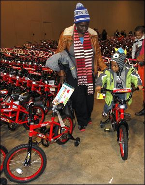Jaron Smith, 3, tries out his new bicycle as his grandmother, Rachelle Ford, watches.