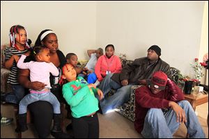 The slaying of Shawn Flowers, 22, is discussed by his sister, Donna Flowers, left, her daughter Alayla, 5; granddaughter ZaNaya, 7, and daughter ZyKeirra, 7. On the couch is Brandon Flowers, 26, and his wife, S’Neta, and the siblings’ grandmother, Hazel Daniels. Brandon’s son, KiViyan, 8, is facing him.  Seated on the floor is Brandon’s brother, Ryan, 24. Shawn’s Sept. 25 slaying was one of 31 in Toledo last year and one of 14 that remains unsolved. Police investigators say they have little information to go on to solve his homicide. Ryan Flowers says somebody knows what happened, but people either don’t care or they are afraid to say anything for fear of retaliation.