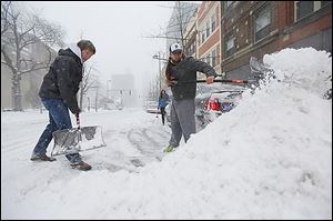 Brad Anderson, left, and Justin Guerrero shovel out their car, stuck on Madison Avenue on Thursday. The scene was a familiar one for many motorists.