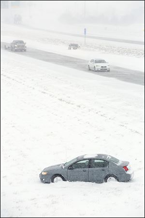 A car sits idle after sliding off  I-75 southbound near the U.S. 23 exit during the  snow storm Thursday. 