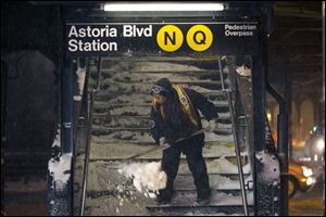 A worker clears snow from a stairway at the Astoria Boulevard subway station in the Queens borough of New York today.