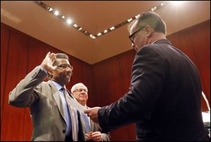 Lt. William Moton takes the oath of office, administered Friday by Adam Loukx, city law director, to become Toledo’s chief of police while Mayor D. Michael Collins looks on at Government Center.