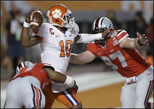 Clemson quarterback Tajh Boyd looks to pass as he is pressured by Ohio State’s Joshua Perry, left, and Joey Bosa, a freshman, who hurt his ankle in the game, but had five tackles and one sack.