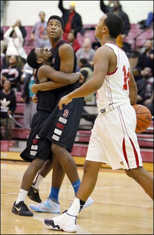 Scott’s Larry Green, left, gets a hug from teammate Percy Bogan after Bogan hit a game-tying shot during the second overtime at Central Catholic.