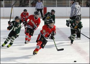 Southgate Senator Jordan Comilla, center, follows the puck during a game against LJK White at the Ottawa Park Ice Rink. The Senator players at first struggled to skate on the rougher ice but adapted. Teams from four states and Ontario took part in the event. 