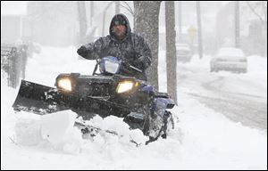 Lewis Gonzales uses his four wheeler to plow snow from the sidewalks on N. Erie near Galena.
