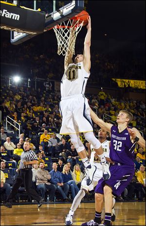 Michigan guard Nik Stauskas dunks the ball above Northwestern forward Nathan Taphorn. Stauskas led the Wolverines with 18 points in Sunday’s victory.