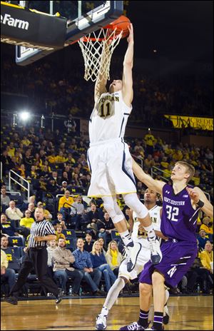 Michigan guard Nik Stauskas (11) dunks the ball while trailed by Northwestern forward Nathan Taphorn (32) in the first half Sunday in Ann Arobr.