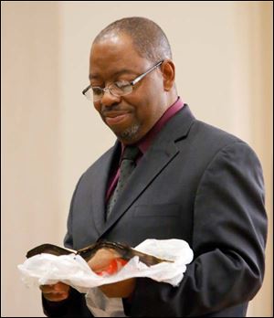 Pastor Curley Johnson of St. Mark Baptist Church looks at a charred bible retrieved from the remains of their church on Detroit Ave.