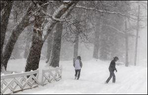 A couple walks through the winter white-out on Swan Avenue in Webster Groves, Mo., Sunday.
